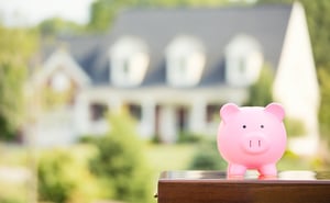 piggy bank with out of focus family home in the background