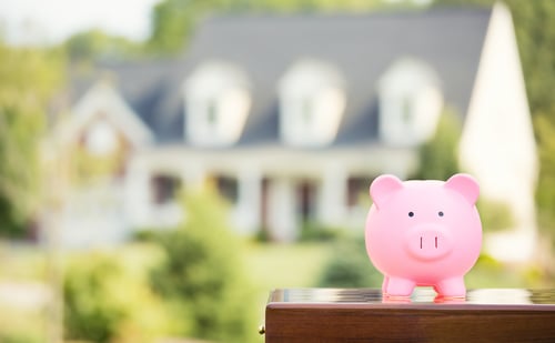 piggy bank with out of focus family home in the background