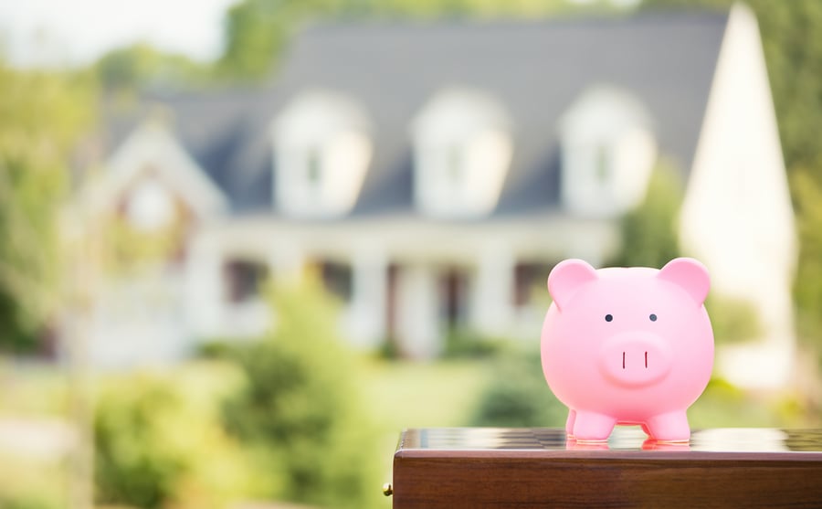 piggy bank with out of focus family home in the background
