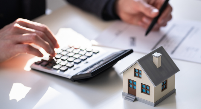 Individual using calculator and filling out documents for home